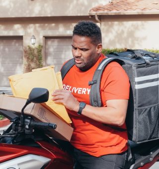 Um motoboy sentado em sua moto com a bag nas costas.